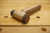 Der fertige selbstgemachte Holzhammer aus einer Messing T-Muffe liegt auf der Werkbank.
