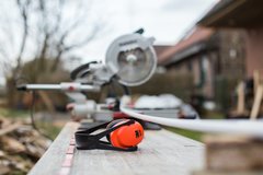 Kapselgehörschutz liegt vor einer Kappsäge